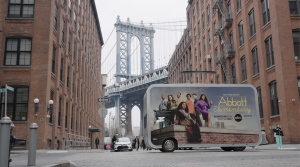 Abbott Elementary tour vehicle resembling a lunchbox drives in front of bridge in New York City.