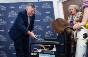 Author Rick Riordan signs a patient in a wheelchair's book.
