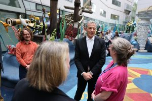 Bob Iger stands with hospital staff in a colorful outdoor play space.