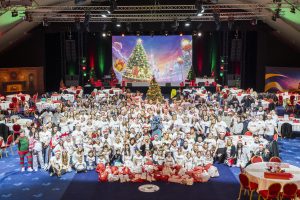 Stitch poses with many Disney VoluntEARS and their families
