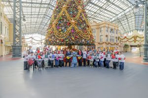 Stitch poses with Tokyo Disney VoluntEARS in front of a Christmas tree