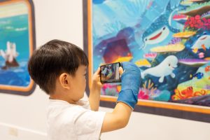 child in cast takes photo of Disney hospital mural
