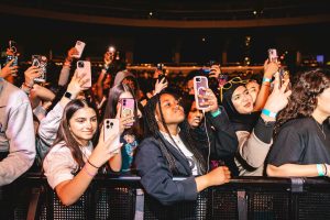 teens in crowd record musical performance on their cell phones