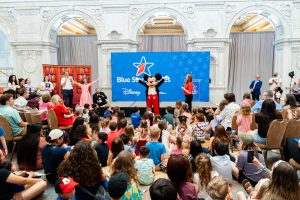 mickey mouse stands in front of room of children