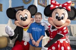 wish kid Paxton smiles next to Mickey and Minnie Mouse