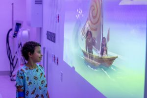 child smiles at Moana characters projected on the wall