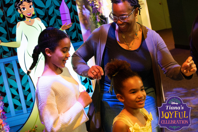 A mom and her two daughters visit Tiana's Joyful Celebration Exhibit