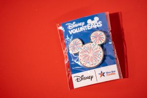 white Mickey Mouse shaped pin with. red and blue fireworks design