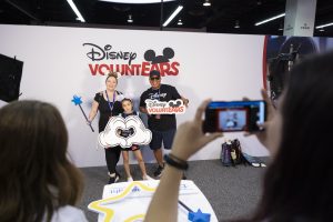 D23 guests pose at Disney VoluntEARS photo booth