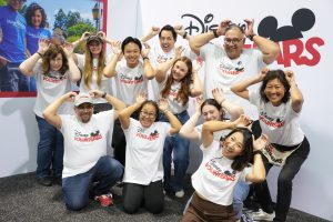 group of Disney VoluntEARS pose, using their hands as Mickey Mouse ears
