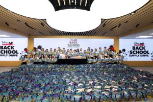 Disney VoluntEARS pose in front of Back to School sign with over 20,000 gifts packed for students