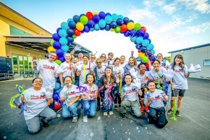 Disney VoluntEARS pose under rainbow balloon arch