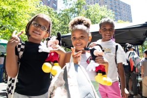 kids pose with Peace signs holding Mickey Mouse plush
