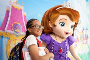 child holding school supplies poses with Sofia the First