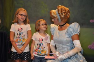 Young Libby and Ella look at Cinderella while she hold their autograph book