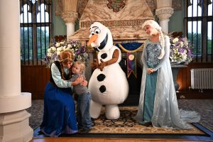child hugs Ana while Olaf and Elsa smile
