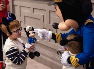 little boy holds Mickey Mouse plush and Captain Mickey points at it